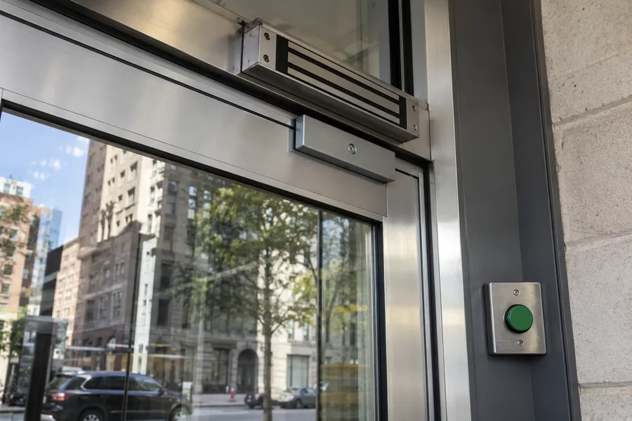 Magnetic lock at the top of a glass storefront door with a push-to-exit button